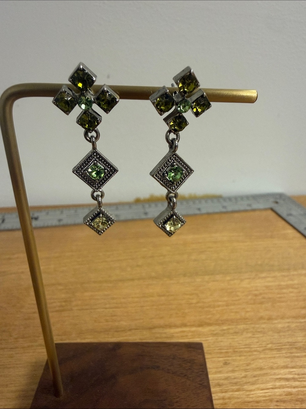 Silver tone metal diamond shaped dangle earrings with green crystal accents